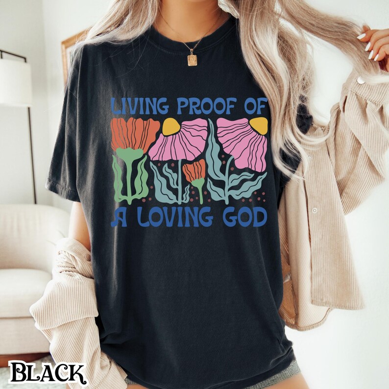 May include: Black t-shirt with a graphic of colorful flowers and the text "Living Proof of a Loving God".