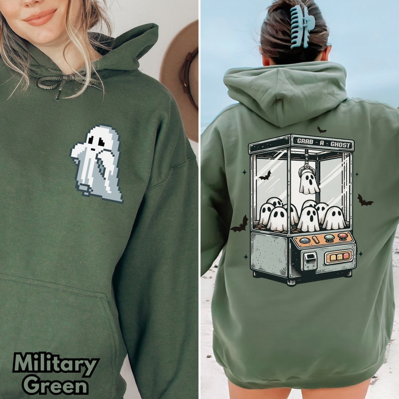Pode incluir: Uma camisa de moletom verde com capuz com um gr&aacute;fico de uma m&aacute;quina de garras fantasma com o texto "Grab-A-Ghost".