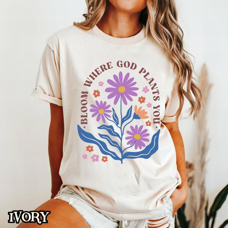May include: A cream-coloured t-shirt with a floral design and the text "Bloom where God plants you."