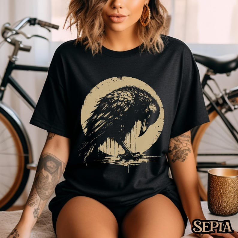 May include: Black t-shirt with a graphic of a crow perched on a moon. The crow is black and the moon is a light beige color.