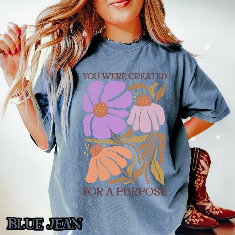 May include: A blue t-shirt with a floral design and the text "You were created for a purpose".