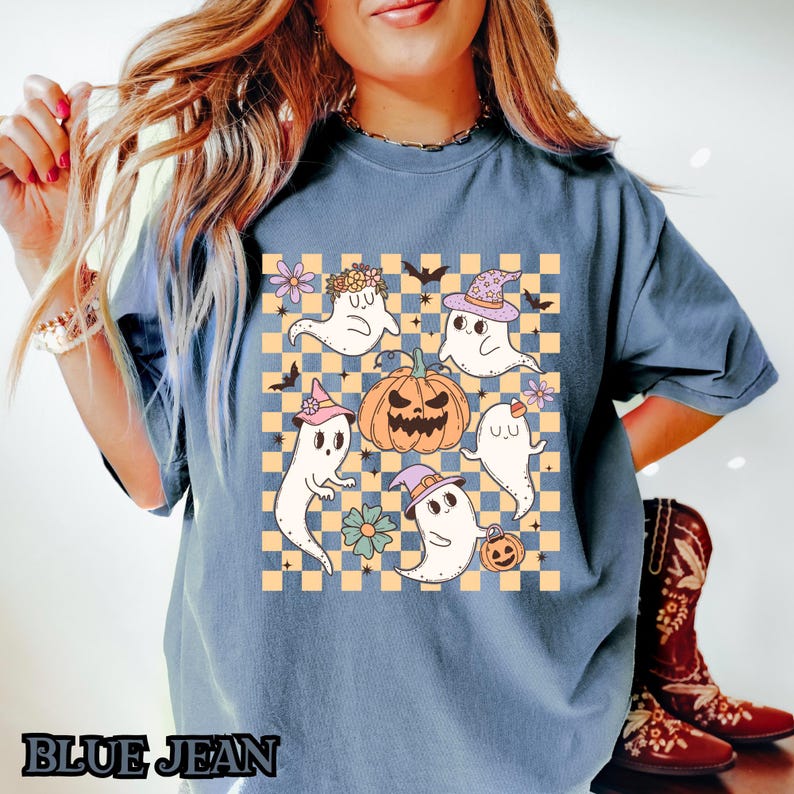 May include: A blue t-shirt with a checkered pattern and a graphic of cute ghosts and a pumpkin. The ghosts are wearing hats and some have flowers on their heads. The text "BLUE JEAN" is at the bottom of the image.