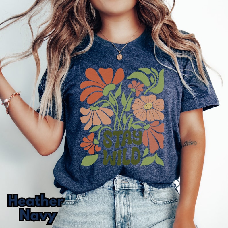 May include: A heather navy blue t-shirt with a floral design and the text "Stay Wild" in green.