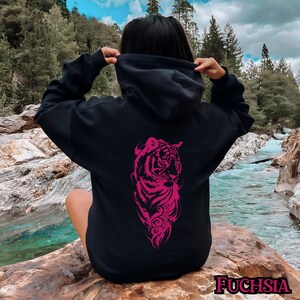 May include: Black hoodie with a pink tiger graphic on the back. The tiger is stylized and has a floral design around it. The hoodie has a drawstring hood.