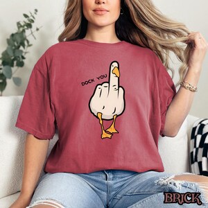 May include: Red t-shirt with a cartoon image of a duck giving the middle finger. The text "Duck You" is printed above the duck.
