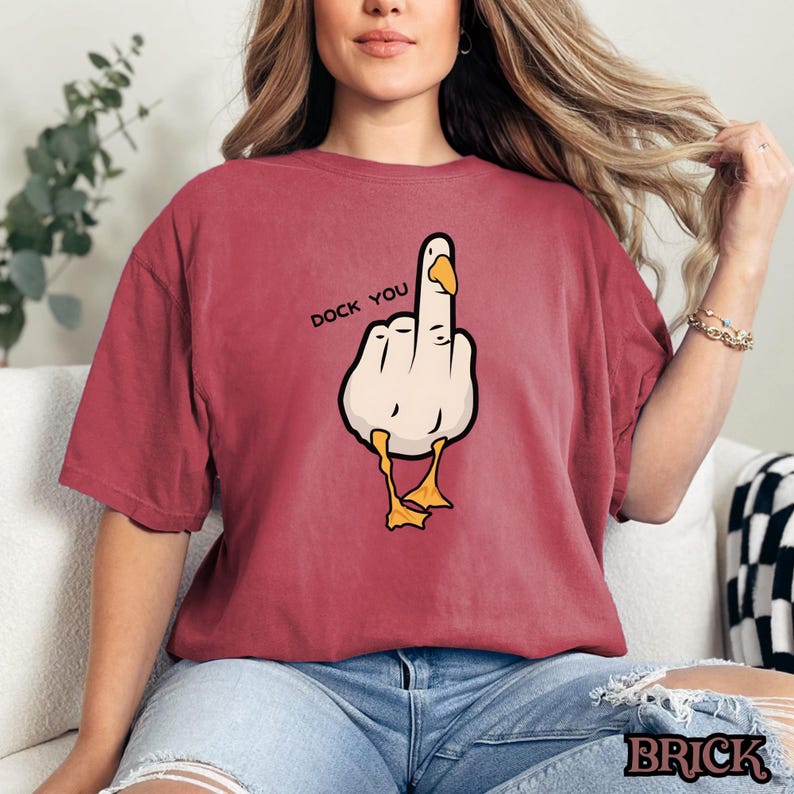 May include: Red t-shirt with a cartoon image of a duck giving the middle finger. The text "Duck You" is printed above the duck.