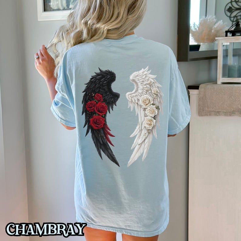 May include: A light blue t-shirt with a graphic of black and white angel wings with red and white roses on each wing.