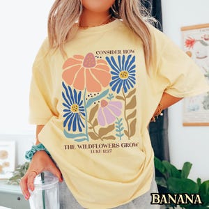 May include: Yellow t-shirt with a floral design and the text "Consider How The Wildflowers Grow Luke 12:27"