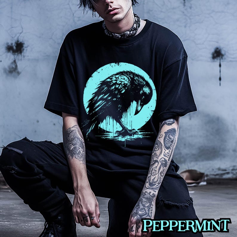 May include: A black t-shirt with a graphic of a black raven in a blue circle. The raven is perched on a branch with its wings spread out.
