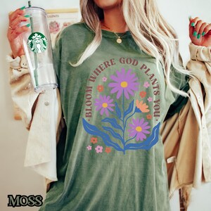 May include: Green t-shirt with a floral design and the text "Bloom where God plants you."