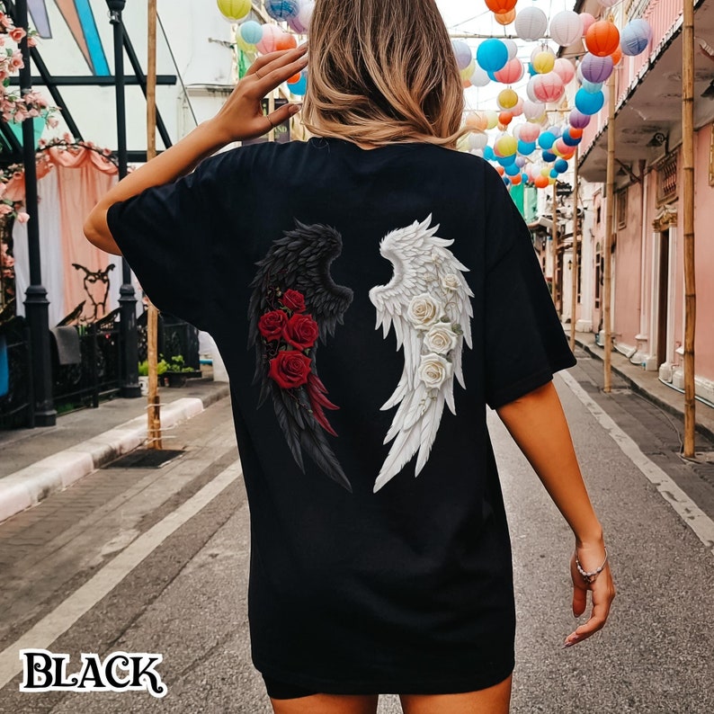 May include: Black t-shirt with a graphic of black and white angel wings with red and white roses on the back. The text "BLACK" is visible at the bottom of the image.