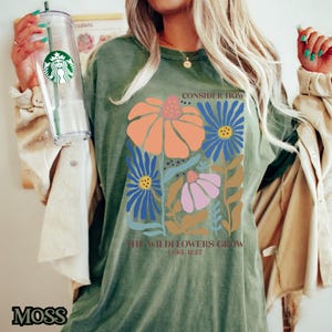 May include: A green t-shirt with a floral design and the text "Consider how the wildflowers grow Luke 12:27".