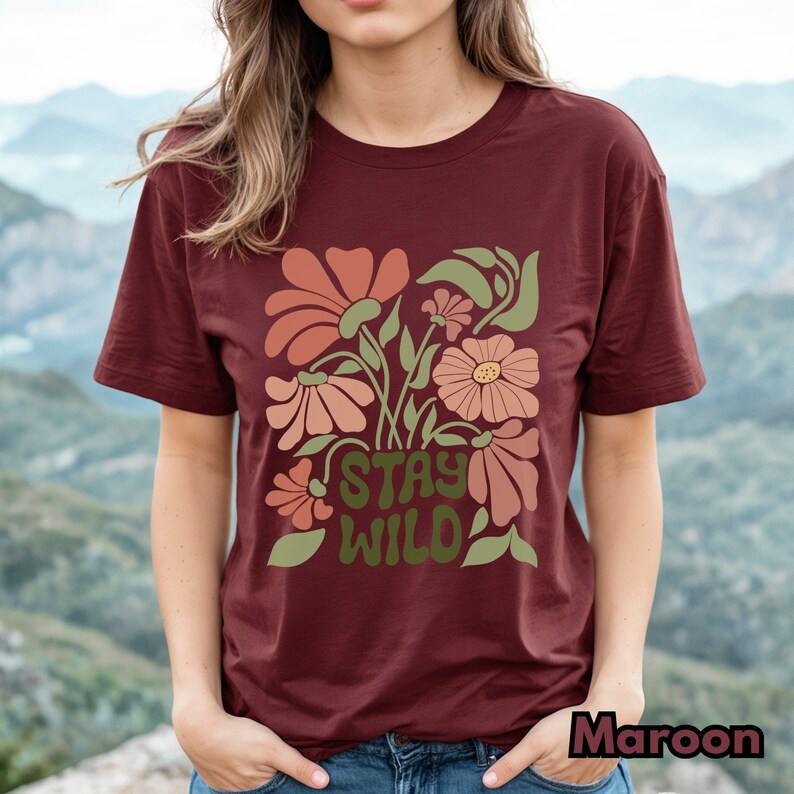 May include: A maroon t-shirt with a floral design and the text "Stay Wild" in green letters.