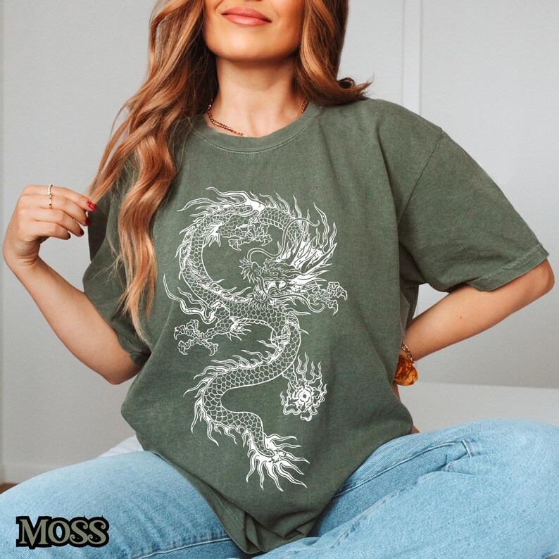 May include: A green t-shirt with a white dragon graphic. The dragon is stylized and has a detailed design.