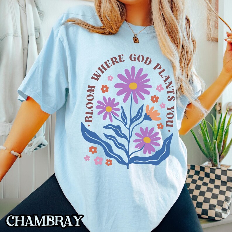 May include: Light blue t-shirt with a floral design and the text "Bloom where God plants you."