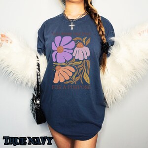 May include: A navy blue t-shirt with a floral design and the text "You were created for a purpose".