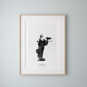 May include: Black and white photograph of a statue of a woman holding a bird in Sofia, Bulgaria.