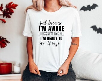 May include: White t-shirt with black text that reads "just because I'M AWAKE DOESN'T MEAN I'M READY TO do things"