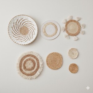 Puede incluir: Un conjunto de siete piezas de decoración mural tejidas en varios tamaños y diseños. Las piezas presentan tonos naturales beige, blanco y marrón, con patrones circulares y en espiral. Algunas tienen flecos o borlas.