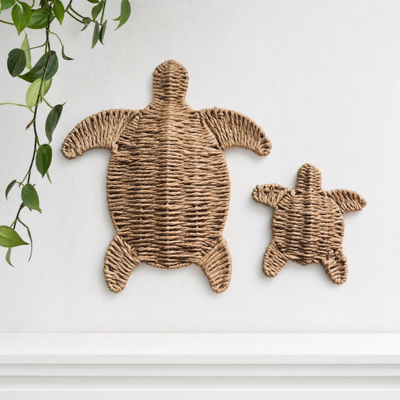 two woven turtle-shaped wall decorations, one larger and one smaller, hanging on a white wall.