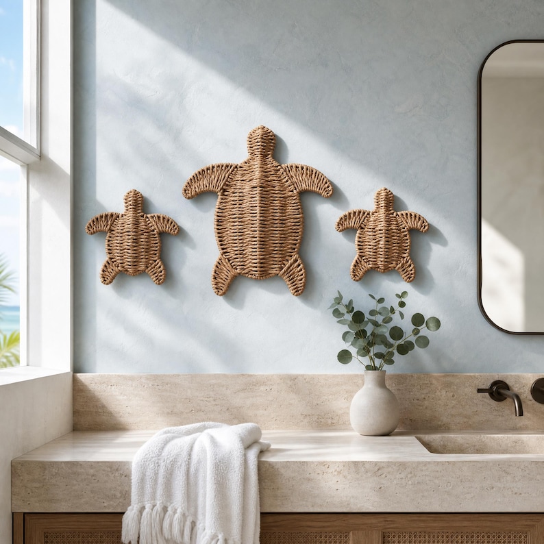 a bathroom with a large mirror, a towel, and a vase with greenery. There are three woven turtle-shaped wall decorations on the wall, and a window can be seen in the background.