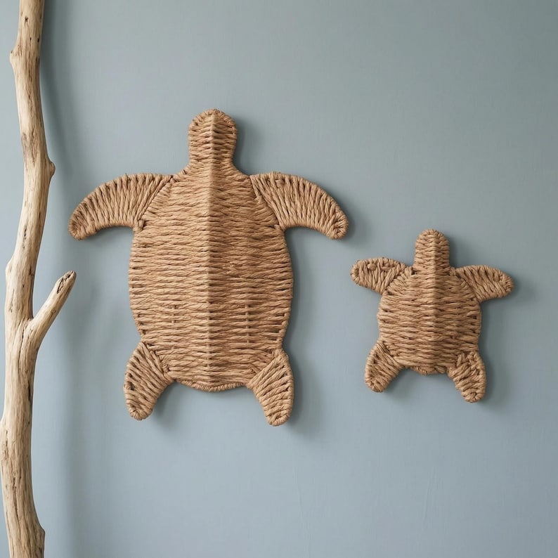 two woven turtle-shaped wall decorations, one larger and one smaller, hanging on a light blue wall.