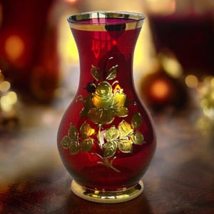 24Kゴールドで作られた花柄の赤いガラスの花瓶。金色の花が咲いた 