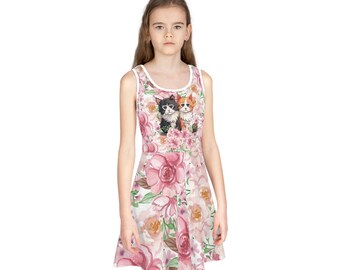 Può includere: Un abito bianco senza maniche con una stampa floreale rosa e due gatti che indossano occhiali da sole. L'abito ha un corpetto aderente e una gonna svasata.