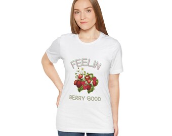 May include: White t-shirt with a graphic of strawberries and the text "Feelin' Berry Good" in a pink and green outline.