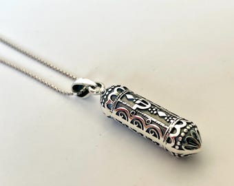 May include: Silver pendant necklace with a detailed, ornate design. The pendant is shaped like a small scroll and features intricate filigree work.