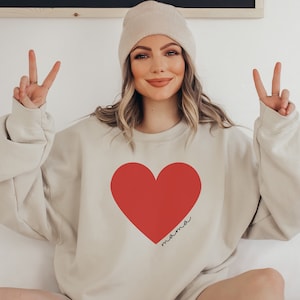 May include: A beige sweatshirt with a large red heart and the word "mama" written inside the heart.