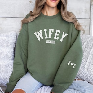 Könnte beinhalten: Grüner Sweatshirt mit dem Text "WIFEY EST. 2024" auf der Vorderseite und "S♥C" auf dem Ärmel.