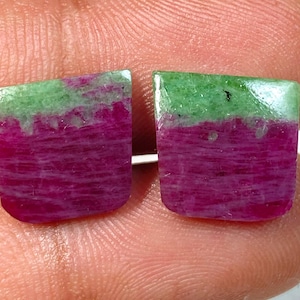 Può includere: Due gemme tagliate quadrate, ciascuna con una vibrante sfumatura di colore. La metà inferiore di ogni pietra è di un magenta intenso, che sfuma in un verde chiaro nella parte superiore. Per gioielli.