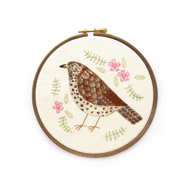 Arte del bordado aro, Zorzal con flores rosadas, enmarcado en un aro de bordar