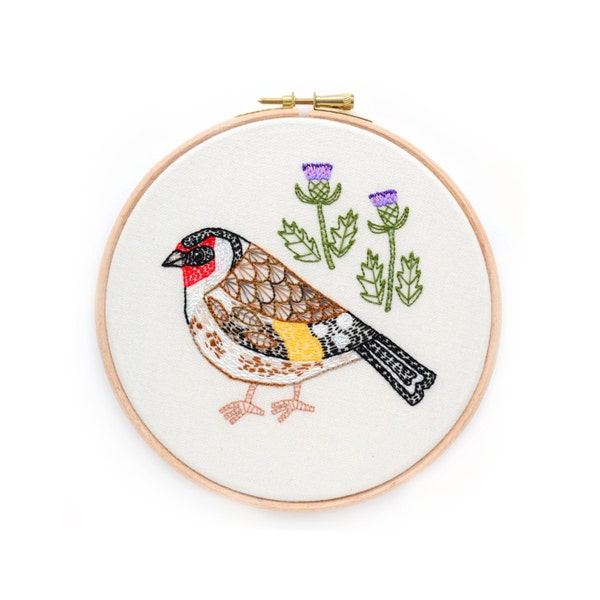 Bordado de un jilguero con cardos, enmarcado en un aro