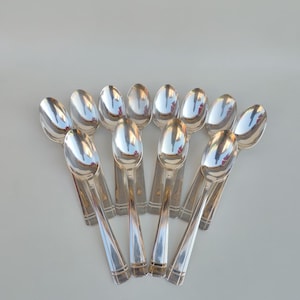 Peut inclure: Un ensemble de dix cuillères à café en argent avec un motif décoratif sur le manche.