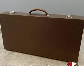 May include: A rectangular brown carrying case with a textured surface, featuring a brown handle at the top center and two silver metal latches on the upper corners. The case has a clean, solid exterior design with visible hardware components.