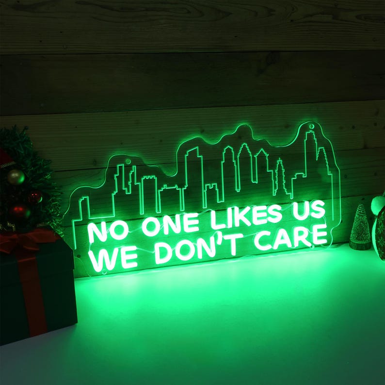 May include: Green neon sign with a cityscape silhouette and the text "No one likes us we don't care".