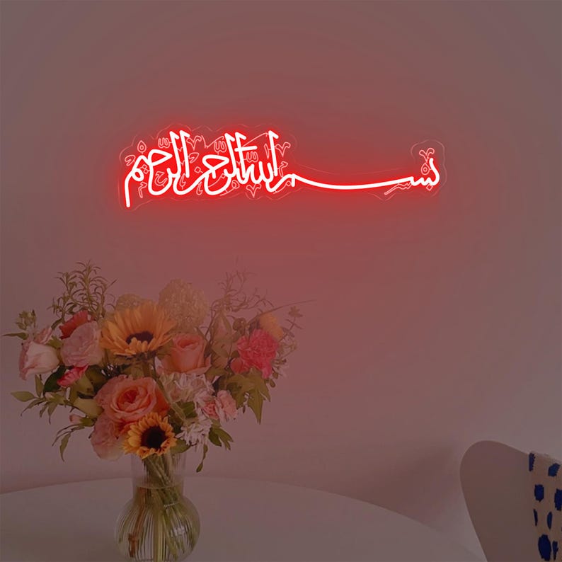 May include: A red neon sign with the Arabic phrase "Bismillah al-Rahman al-Rahim" which translates to "In the name of Allah, the Most Gracious, the Most Merciful".