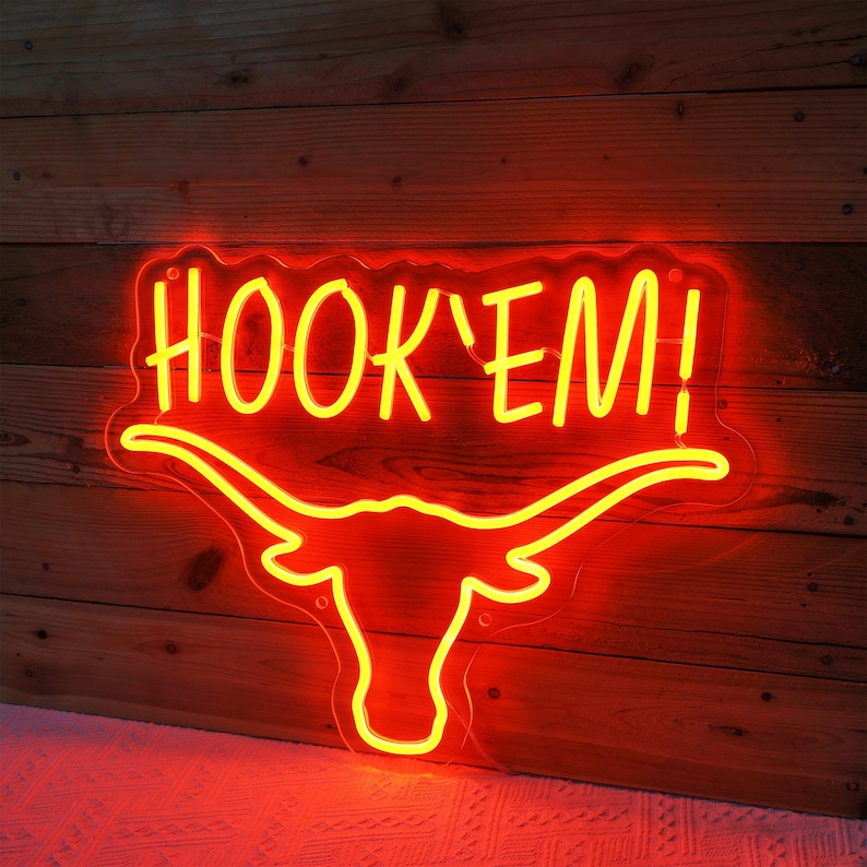May include: Neon sign with a yellow "HOOK'EM!" text and a red outline of a longhorn bull's head.