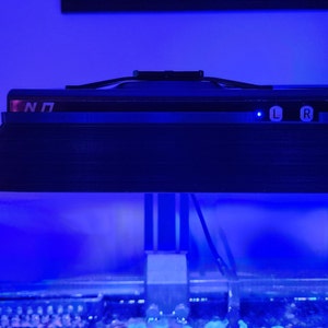 May include: A black aquarium light with a blue light shining down on the water. The light has a control panel with buttons labeled "L" and "R".