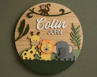 May include: A circular wooden wall sign featuring the name Colin John in white lettering. The design includes layered cutouts of a brown monkey on a branch, a yellow giraffe, a yellow and orange lion, and a gray elephant, all set against green foliage.