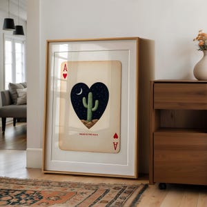 May include: Framed art print featuring an Ace of Hearts playing card design. The card showcases a heart-shaped image of a cactus under a starry night sky. The text "MADE IN THE U.S.A." is printed at the bottom of the card.