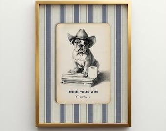 May include: A framed wall art piece featuring a black and white illustration of a bulldog wearing a cowboy hat, sitting on a stack of books next to a roll of toilet paper. The text reads MIND YOUR AIM and Cowboy, set against a blue striped background.