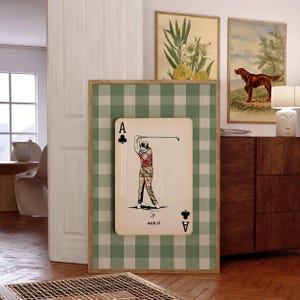 K&ouml;nnte beinhalten: Ein rechteckiges Wandbild mit einem gr&uuml;n-wei&szlig;en Vichy-Karo-Hintergrund und einer mittigen Spielkartengrafik. Die Karte zeigt die Illustration eines Golfers in kariertem Outfit beim Abschlag, mit dem Schriftzug ACE IT am unteren Rand.