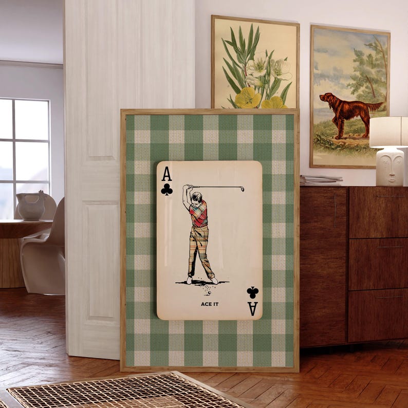 K&ouml;nnte beinhalten: Ein rechteckiges Wandbild mit einem gr&uuml;n-wei&szlig;en Vichy-Karo-Hintergrund und einer mittigen Spielkartengrafik. Die Karte zeigt die Illustration eines Golfers in kariertem Outfit beim Abschlag, mit dem Schriftzug ACE IT am unteren Rand.
