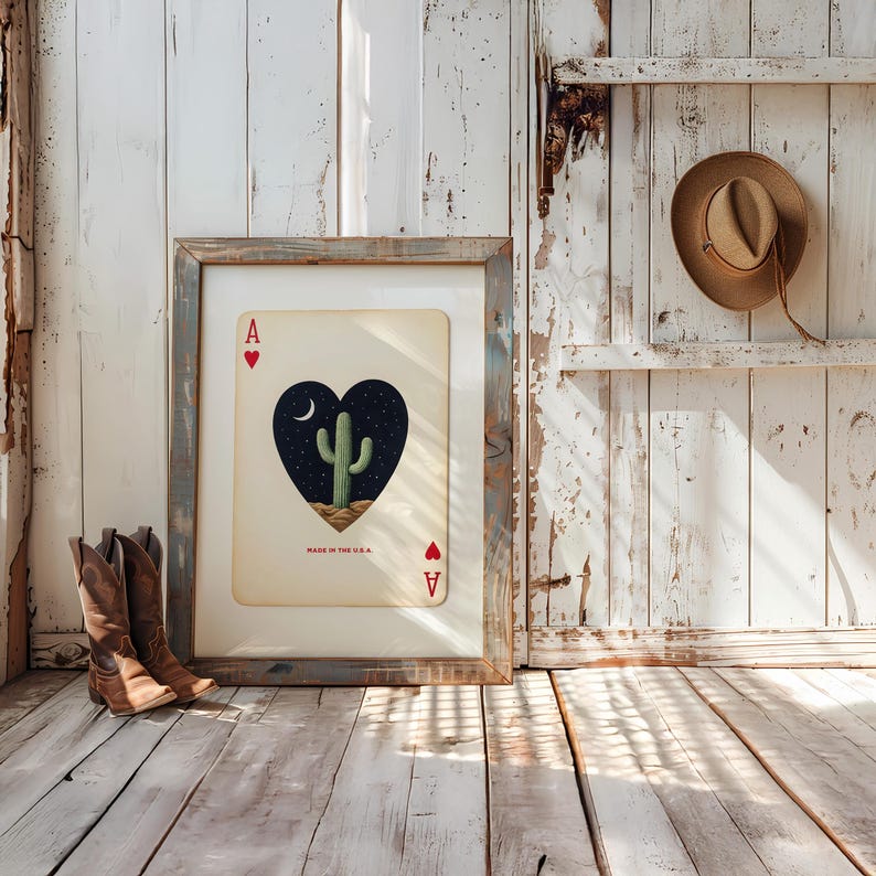 May include: Framed Ace of Hearts playing card art featuring a cactus under a starry night sky. The card is framed in a rustic, weathered wood frame. The text "MADE IN THE U.S.A." is visible. Brown cowboy boots are in the foreground.