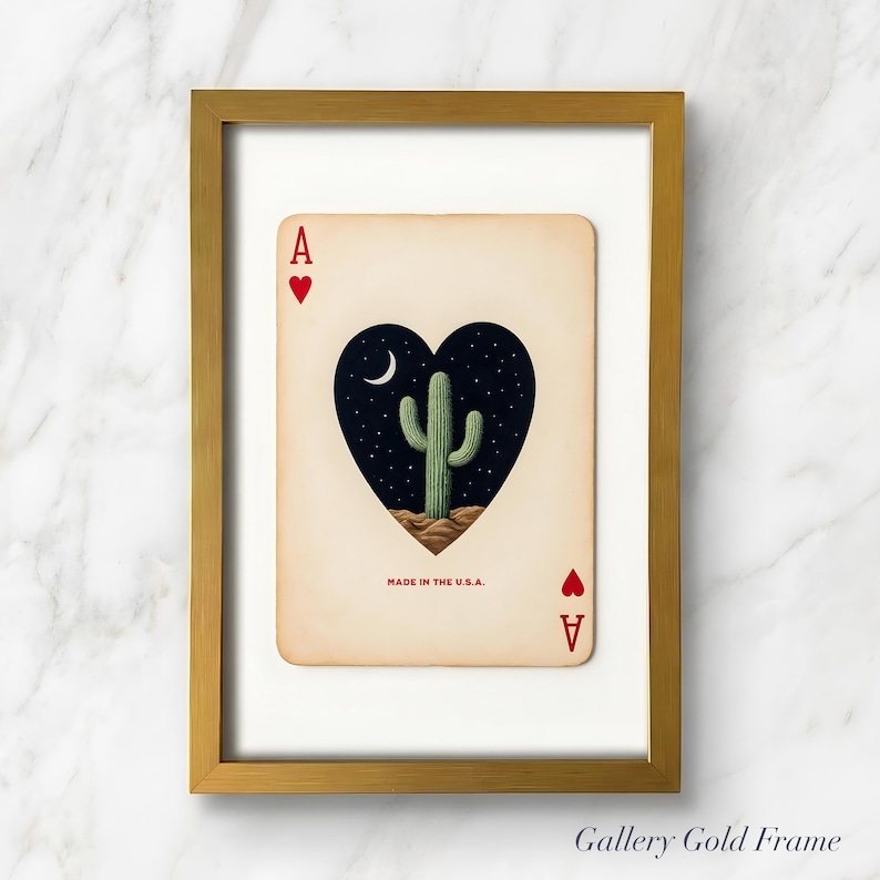 May include: Ace of Hearts playing card art print. The card features a heart-shaped design with a cactus under a crescent moon and starry night sky. The card is framed in a gold frame and reads "MADE IN THE U.S.A."