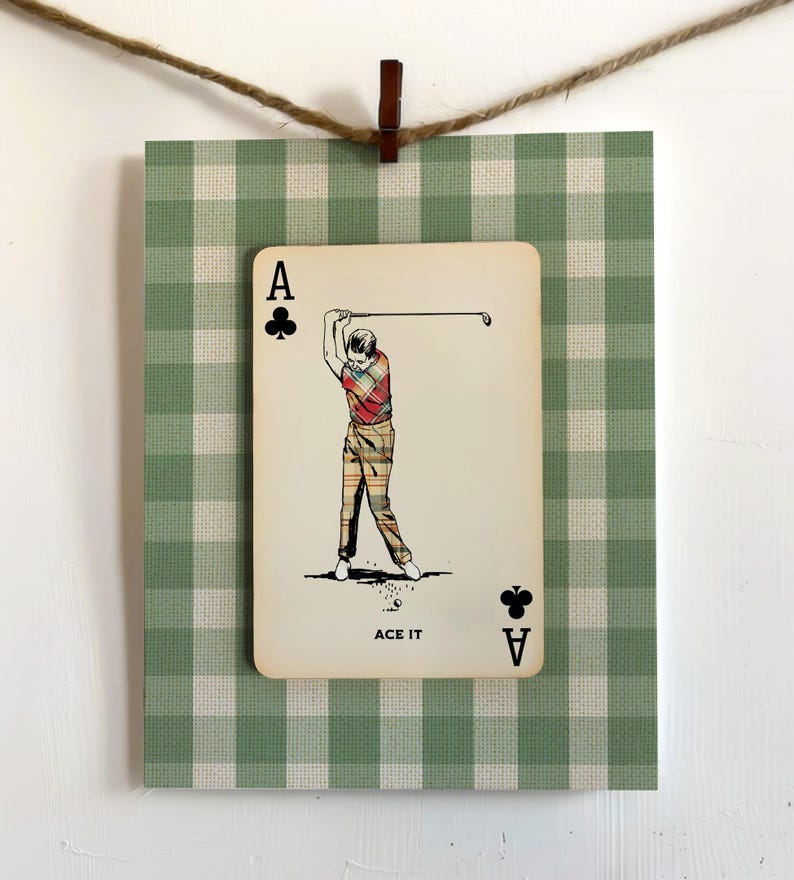 K&ouml;nnte beinhalten: Eine rechteckige Karte mit einer Illustration im Vintage-Stil eines Golfers, der einen Schl&auml;ger schwingt, vor einem gr&uuml;n-wei&szlig;en Vichy-Karo-Hintergrund. Die Karte zeigt den Text ACE IT sowie den Buchstaben A mit einem Kreuz-Symbol.