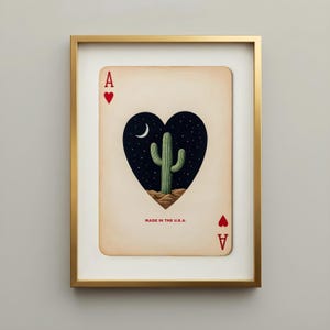 Framed art print of the Ace of Hearts playing card. The card features a heart-shaped cutout revealing a desert scene with a saguaro cactus, moon, and stars. The text "MADE IN THE U.S.A." is printed at the bottom. Cool apartment decor. Trendy wall art.